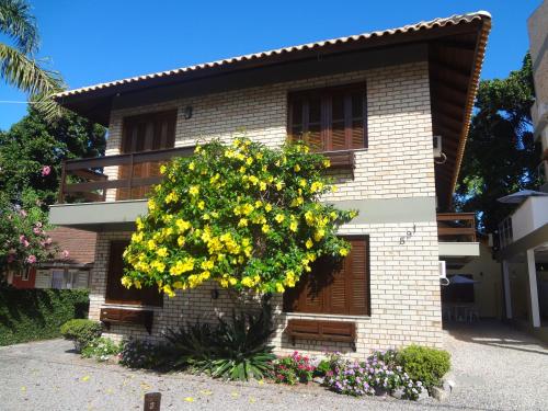 un edificio con un árbol florido delante de él en Bombinhas Quinta do Mar Complexo A, en Bombinhas