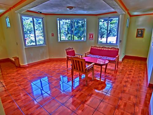 a living room with a table and chairs and windows at Hotel El Sol in Panajachel