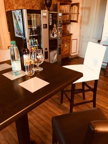 a table with two white chairs and a refrigerator at Le Domaine du Chêne Vert in Château-Gontier