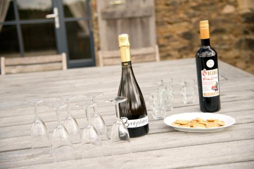 two bottles of wine and glasses on a wooden table at Gîtes la Bréjolière in Saint-Maurice-des-Noues
