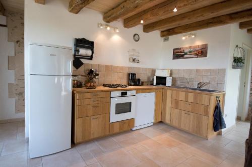 a kitchen with a white refrigerator and wooden cabinets at Gîtes la Bréjolière in Saint-Maurice-des-Noues