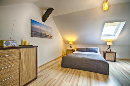 a bedroom with a bed and a dresser and a window at Apartamenty Pod Dębem in Wicie