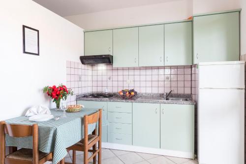 a kitchen with white cabinets and a table with chairs at Happy Days in Capo Vaticano