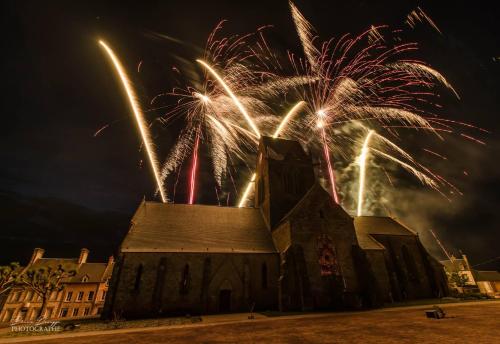 a church with fireworks exploding in the sky behind it at Gite le Sainte Mère Eglise in Sainte-Mère-Église