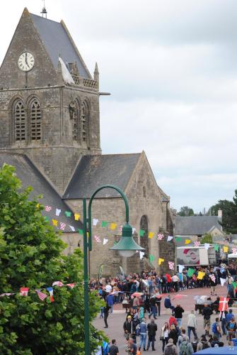 a crowd of people standing in front of a church at Gite le Sainte Mère Eglise in Sainte-Mère-Église