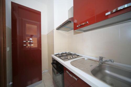 una cucina con lavandino e porta rossa di Buona Vacanza a Borghetto Santo Spirito