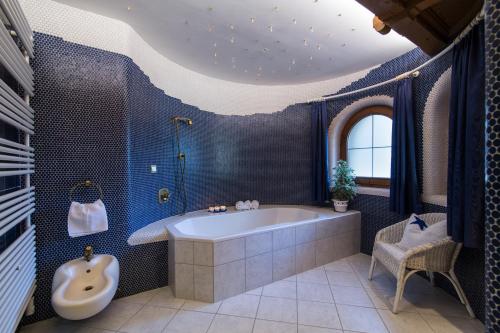 een blauwe badkamer met een bad en een stoel bij Am Eschenbichl in Mayrhofen