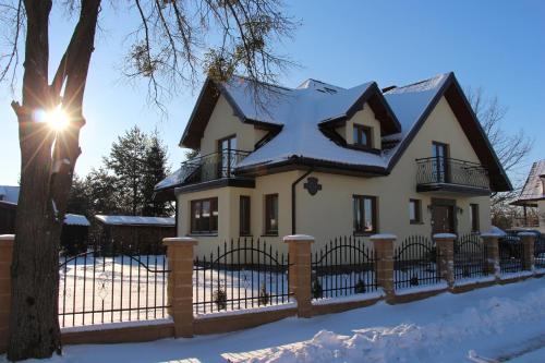 a house with a fence in the snow at Pokoje Gościnne Сisza in Białowieża