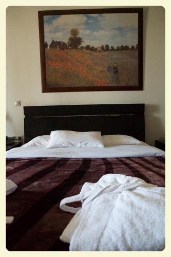 a bedroom with a bed with a painting on the wall at Nymfes Hotel in Kato Loutraki