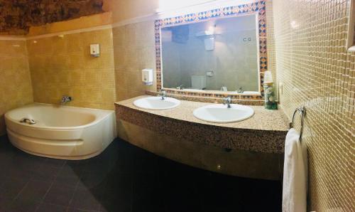 a bathroom with two sinks and a tub and a mirror at Hostal Posada La Panadera in Sepúlveda