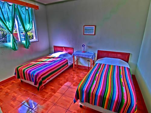 a room with two beds and a table and a window at Hotel El Sol in Panajachel