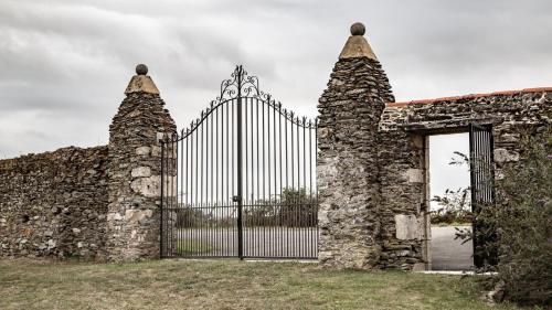 an entrance to an old stone building with a gate at Gîtes la Bréjolière in Saint-Maurice-des-Noues