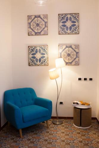 a blue chair in a room with paintings on the wall at Isa Guest Rooms in Naples