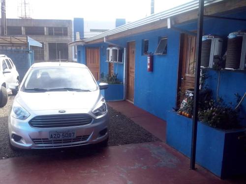 een witte auto geparkeerd naast een blauw gebouw bij Pousada MG in Foz do Iguaçu
