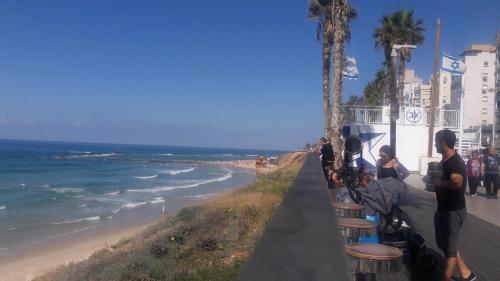 a group of people standing on a sidewalk near the beach at Hotel Apartment TLV-bat yam 81 in Bat Yam