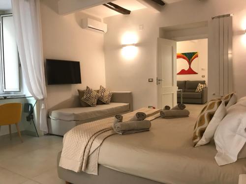 ナポリにあるNapoli Plebiscito Apartmentのベッド2台とソファが備わるホテルルームです。