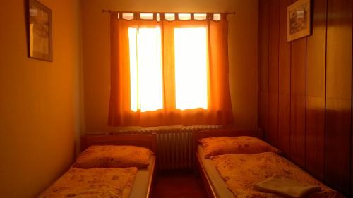 a bedroom with two beds in front of a window at Penzion Lipůvka in Lipova Lazne