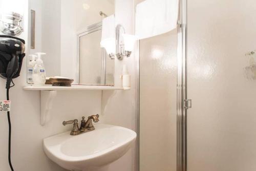 a white bathroom with a sink and a shower at The Coolidge Corner Guest House: A Brookline Bed and Breakfast in Brookline
