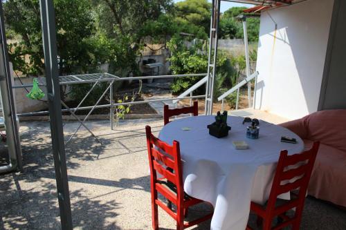 a white table with two red chairs and a white table with a view at Surfers' Cottage in Anavissos