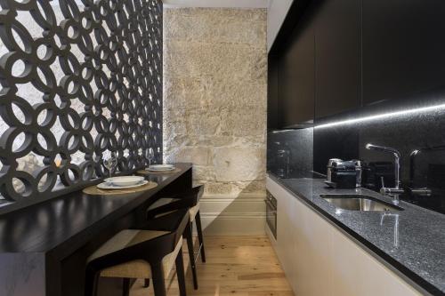 a black kitchen with a sink and some chairs at Santa Catarina Apartments in Porto