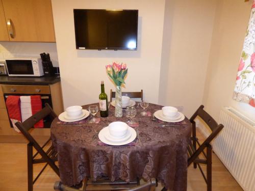 a dining room table with a bottle of wine and flowers at Birdholme House in Chesterfield