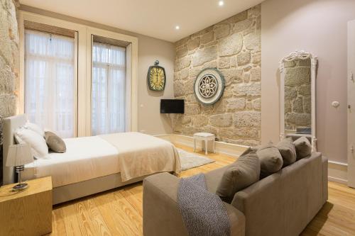 a bedroom with a bed and a couch and a stone wall at Ribeira Historic Apartments in Porto