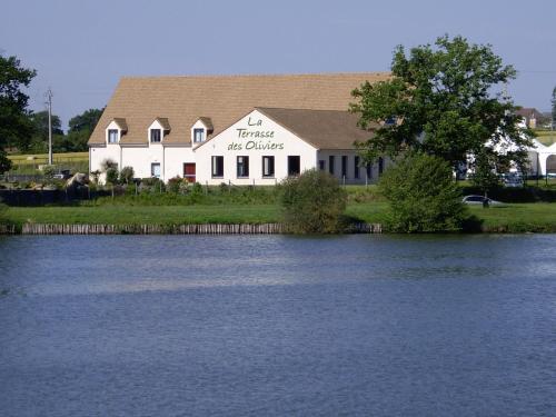 a house with a sign on it next to a lake at La Terrasse des Oliviers in Mansigné