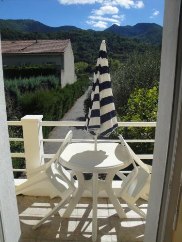 a table and two chairs with an umbrella on a balcony at Hôtel La Caravelle in Nyons