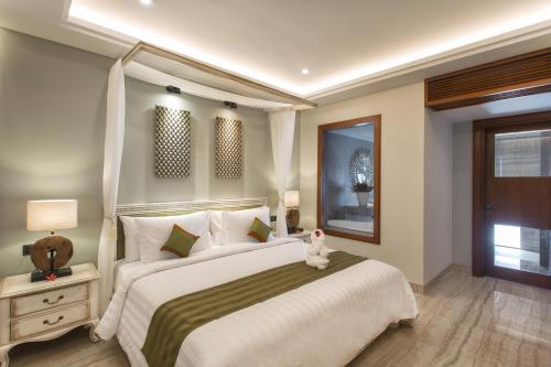 a bedroom with a large bed with a teddy bear sitting on it at Sense Canggu Beach Hotel in Canggu