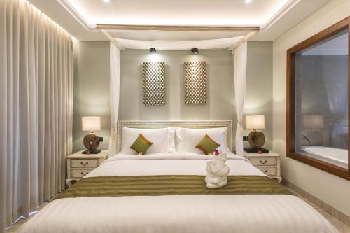 a bedroom with a bed with a teddy bear sitting on it at Sense Canggu Beach Hotel in Canggu