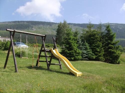 a playground with a yellow slide in a field at Pension 48 in Špindlerův Mlýn