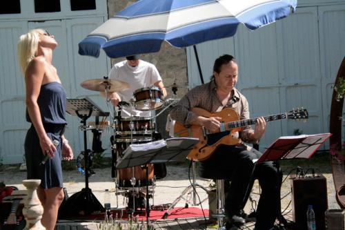 a man playing guitar and drums under an umbrella at La Grange en Champagne in Hermonville