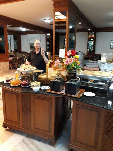 un hombre parado detrás de un mostrador con comida en Royal Palace Hotel, en Pattaya central