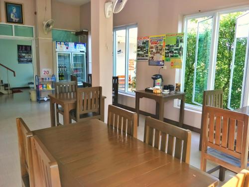 a dining room with a table and chairs and windows at Blue House Sukhothai in Sukhothai