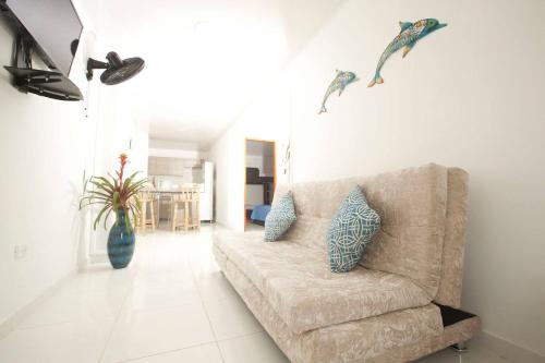 a living room with a couch and two dolphins on the wall at Apartamentos Chalet del Mar in San Andrés