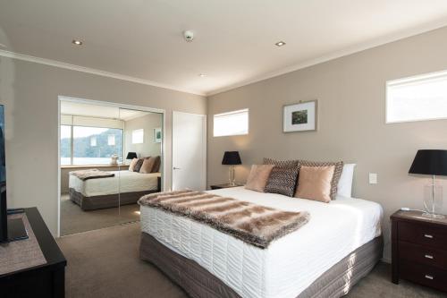 a bedroom with a large bed and a mirror at Picton Waterfront Penthouse in Picton