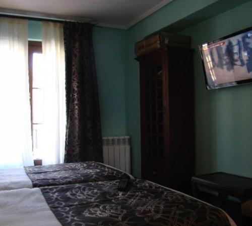 a bedroom with a bed and a television on the wall at Hotel-Hospedería los Templarios in Sepúlveda