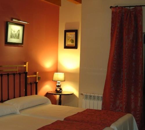 a bedroom with a bed and a table with a lamp at Hotel-Hospedería los Templarios in Sepúlveda