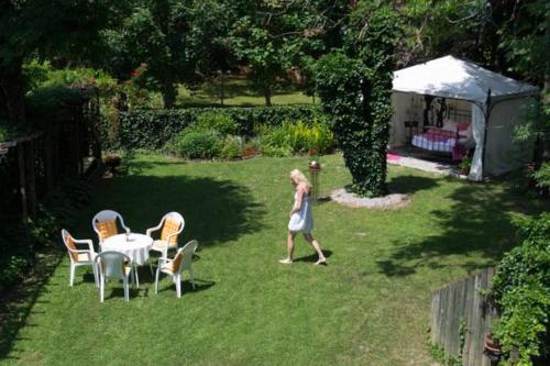 a woman walking through a yard with a table and chairs at Pension Stissen Haus am See in Faak am See