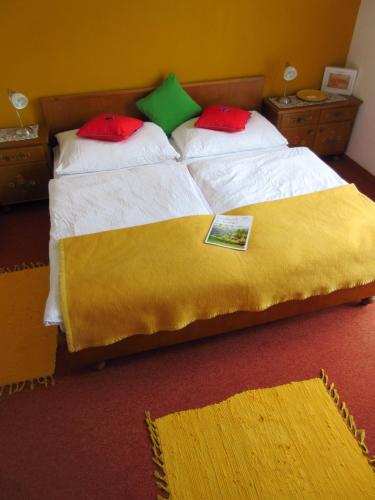 a bedroom with a large bed with a yellow blanket at Pension Stissen Haus am See in Faak am See