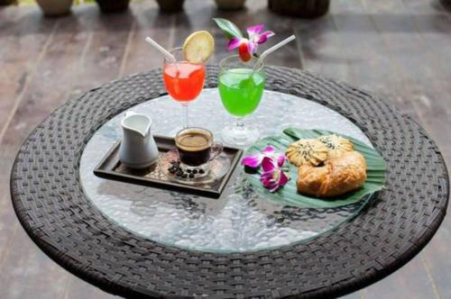 ein Glastisch mit zwei Getränken und einem Tablett mit Essen in der Unterkunft Khao Sok Green Valley Resort - SHA Certified in Khao Sok