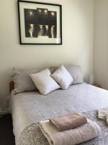 een slaapkamer met een bed met kussens en een foto aan de muur bij Nextdoor@portarthur in Port Arthur