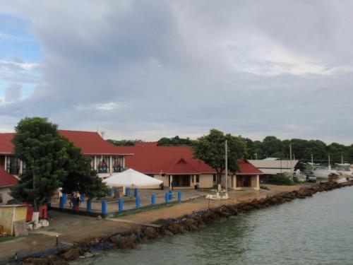 a group of buildings with red roofs next to a river at Memories Cottage and Apartments in Buccoo