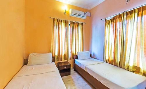two beds sitting in a room with windows at Shoba Suites-Kammanahalli in Bangalore