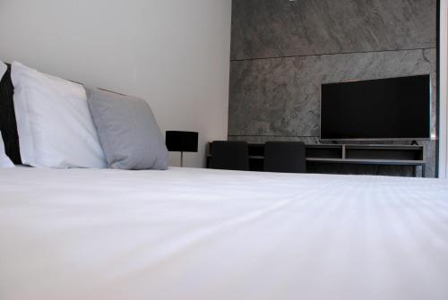 a bedroom with a white bed and a flat screen tv at La Perla by Sedar in Como