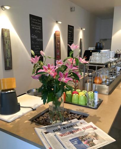 a counter with a vase with pink flowers on it at Hotel Alexander in Wiesbaden