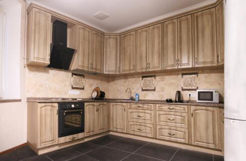 a kitchen with wooden cabinets and a microwave at Apartment on Lukyanovska in Kyiv