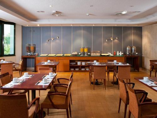 a restaurant with tables and chairs and a kitchen at Apartamentos TH Las Rozas in Las Rozas de Madrid