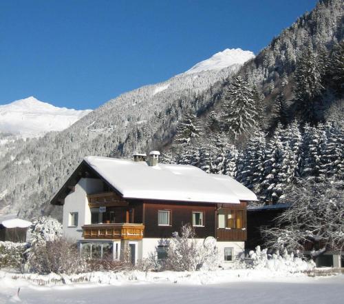 a house covered in snow in front of a mountain at Haus Rudigier by Châtel Reizen in Sankt Gallenkirch