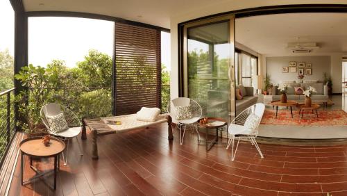 a balcony with white chairs and a living room at Bungalow 99 in New Delhi